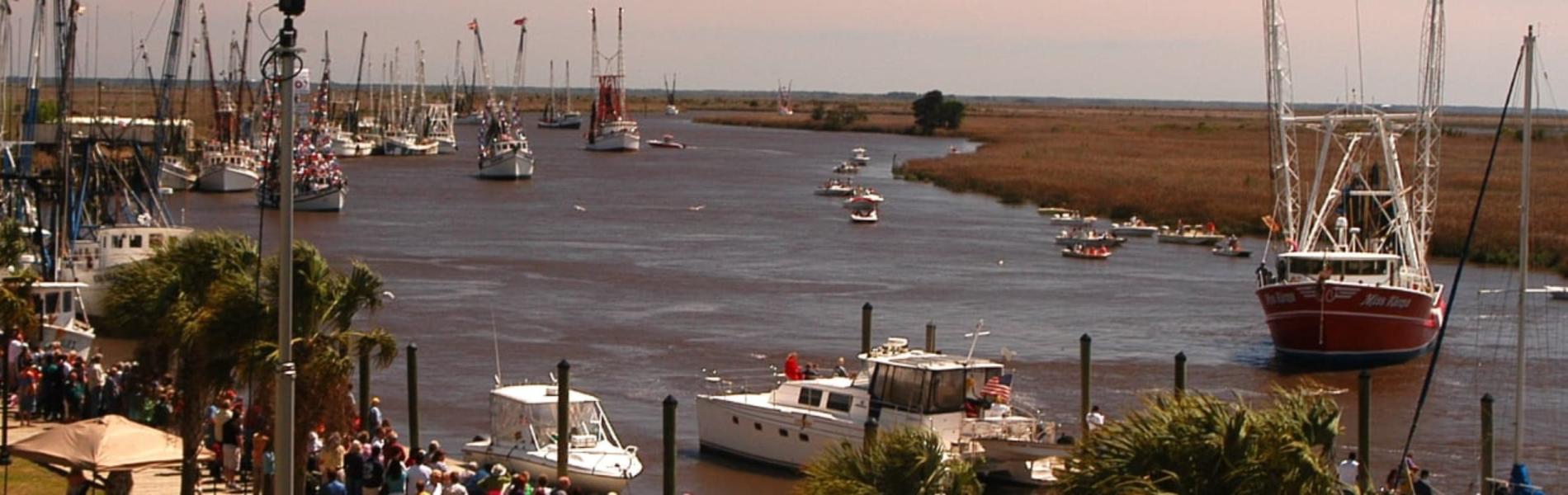 Boats on a calm river with grassy banks and a distant marshland background.
