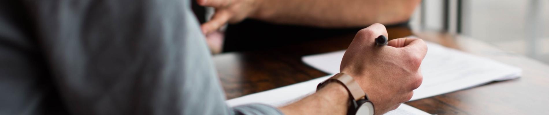 Two people discussing over a document at a wooden table.